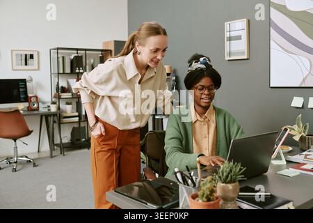 Black Woman Working on Laptop with Female Manager in Office Stock Photo