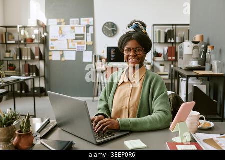 Portrait of Black Adult Woman Working on Laptop in Creative Office Stock Photo