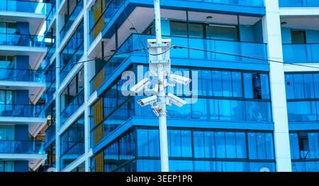 Multiple security cameras on a pole against a modern blue glass building Stock Photo