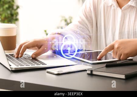 Woman working with laptop and tablet computer at her workplace in office, closeup. Antivirus concept Stock Photo