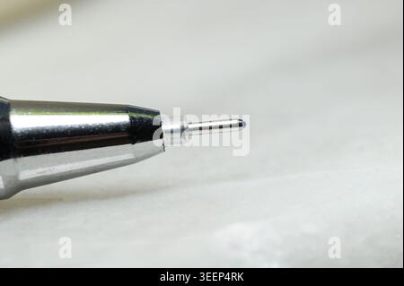 Close-up macro shot of a ballpoint pen tip with blue ink ready to write Stock Photo