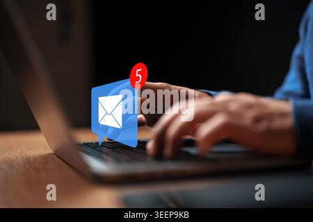 Person checks email notifications on laptop with five new messages at home office in evening Stock Photo