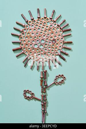 Metal bolts and nuts arranged as abstract flower shape on mint background in minimal style Stock Photo