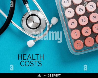 Stethoscope and calculator on blue background with the text health costs, illustrating healthcare finance, medical expenses, and insurance costs Stock Photo