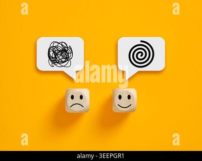 Mental confusion and clarity concept with messy tangled line and organized spiral icons on wooden blocks over yellow background Stock Photo