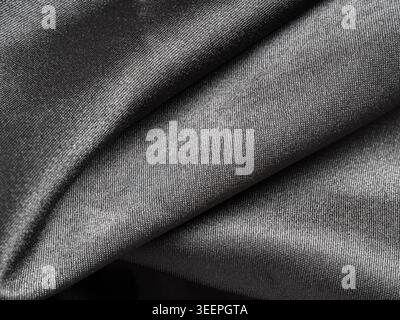 Dark gray shiny fabric creating elegant and luxurious folds, highlighting smooth and soft textile texture background Stock Photo