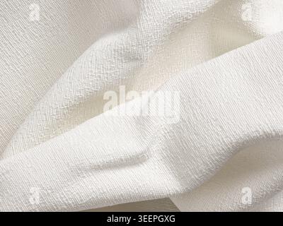 White, textured, woven cotton fabric displaying gentle waves and soft folds, creating a clean abstract background Stock Photo