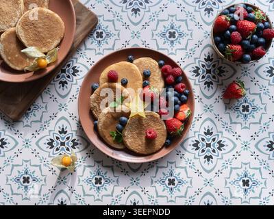 Overhead view of pancakes topped with berries and figs on patterned tile surface Stock Photo