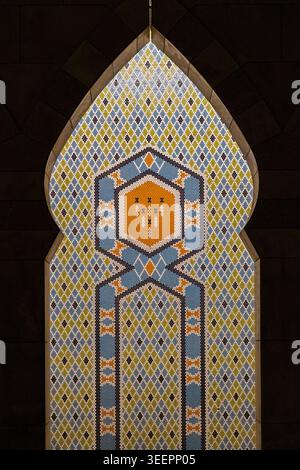 Intricate geometric Islamic mosaic tile panel in pointed arch, blue gold and orange pattern, mosque interior, Saudi Arabia or Oman Stock Photo