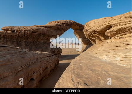 Close-up view through Rainbow Rock natural sandstone arch framing distant desert and rock formations, AlUla region, Saudi Arabia Stock Photo