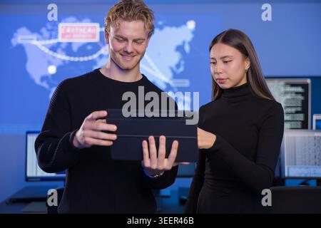 Two cybersecurity analysts collaborating in a modern SOC environment with digital maps Stock Photo