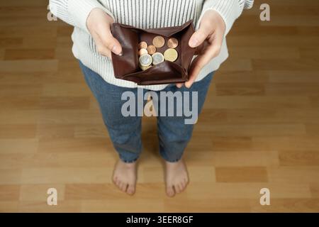 Barefoot person holding a coin pouch, modest income or financial carefulness. Stock Photo