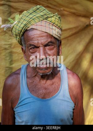 Portrait of an elderly man wearing a yellow headdress in a rural village in Odisha, India Stock Photo