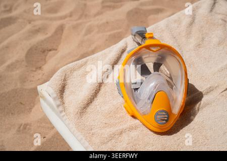 Yellow full face snorkeling mask on beach lounge chair prepared for underwater swimming and reef exploration. Snorkeling equipment and marine recreati Stock Photo