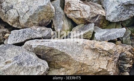 Close up on various sized rocks, piled together with rough textures, mossy patches. Soft, diffuse lighting highlighting natural stone colors. Useful f Stock Photo