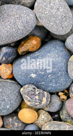 Pile of smooth river stones, shot with neutral lighting. Colorful textures and shapes create visual interest, ideal for backgrounds. Promotes calm, ba Stock Photo
