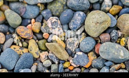 Close up shows stones in mix of natural earth tones. Includes blues, yellows, oranges, and grays. Focus on organic shapes and textures. Great for back Stock Photo