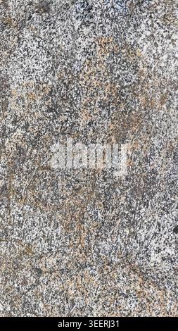Close up shows granite rock with fine grained speckled texture. Neutral gray, white and small orange tones. Good for backgrounds, construction or geol Stock Photo