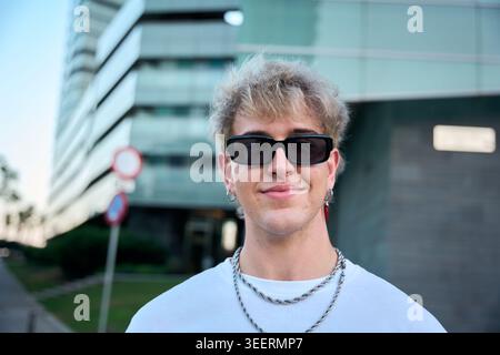 Blond gen z influencer smiling wearing sunglasses and silver chains Stock Photo