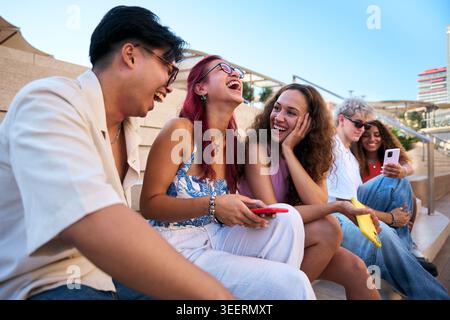 Young people sharing funny content on smartphone in urban setting Stock Photo