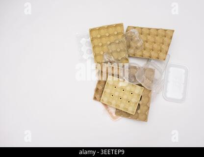 An overhead shot shows a messy jumble of various recyclable containers, including different sized pulp egg cartons, clear plastic containers, and a fo Stock Photo