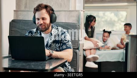 Freelancer, headphones and man in camper van on laptop for travel blog, copywriting or remote work. Mobile home, family and person on computer for Stock Photo