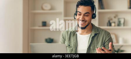 Man Engages in Online Meeting Using Laptop While Wearing Headset in Modern Room Stock Photo
