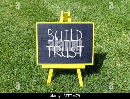 Build trust symbol. Concept words Build trust on beautiful black blackboard. Beautiful green grass lawn background. Business and build trust concept, Stock Photo