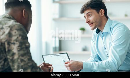 Meeting Between Two Men in an Office Discussing a Document With Clear Focus on Conversation Stock Photo