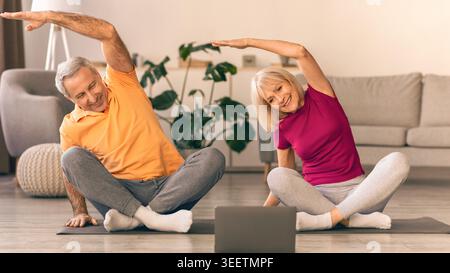 Seniors Doing Stretching Exercises at Home While Following Online Workout Routine Stock Photo