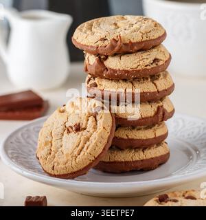 Homemade cookies with chocolate chunks and peanut butter.  A stack of biscuits in a white plate, a coffee pot and a cup on the table. Selective focus, Stock Photo