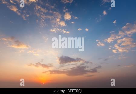 A stunning sunset sky filled with colorful clouds fades to twilight, creating a serene and picturesque scene at dusk. Stock Photo