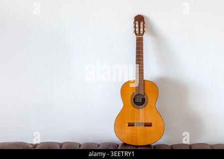 Classical Spanish guitar leaning against white wall with copy space Stock Photo