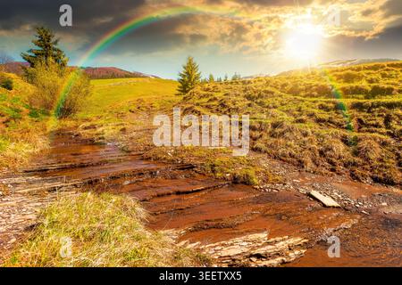 sunset over rural scenery in carpathian mountains. simple view of a countryside mountain landscape during springtime. brook near the grassy hills. wea Stock Photo