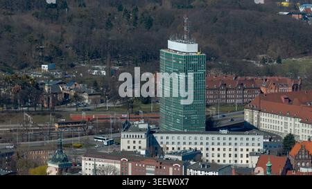 Aerial view of Gdansk's urban landscape featuring a striking green modern office tower rising above historic red-brick buildings and Stock Photo