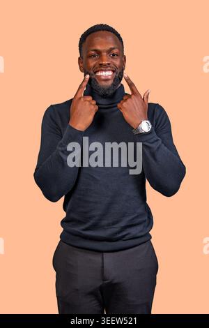 Happy young man smiling, gesturing towards his healthy bright white teeth Stock Photo