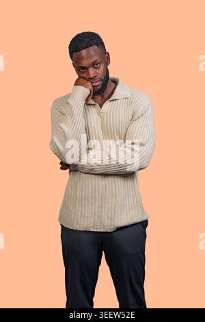 Young black man in casual sweater pondering with hand resting on his chin Stock Photo
