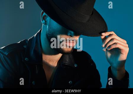 Fashion, hat and man in studio with thinking for elegant, creative or trendy style with glow. Aesthetic, stylish or confident with male person for Stock Photo