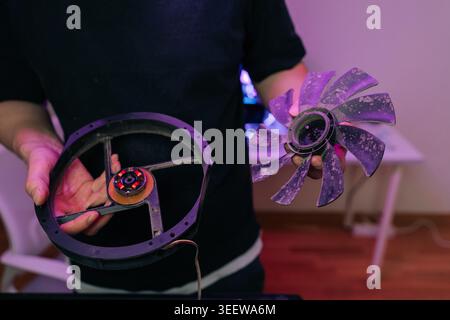 Man holding dirty disassembled computer cooling fan. Dusty blades motor with red lights shown separately. Concept for PC hardware maintenance Stock Photo