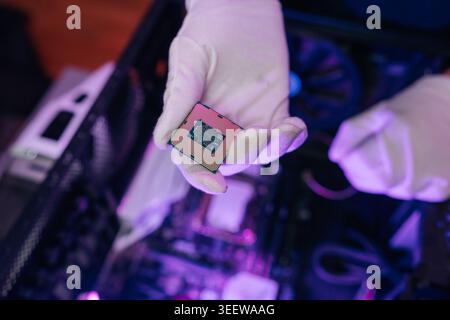 Technician gloved hand holding central processing unit, showcasing intricate design of semiconductor hardware against blurred backdrop of internal Stock Photo