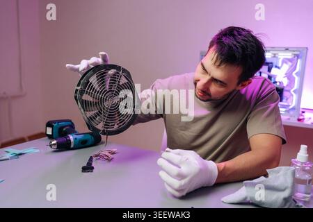 Technician in white gloves holding dusty CPU cooling fan removed from pc chassis, inspecting and preparing hardware for cleaning and maintenance in Stock Photo