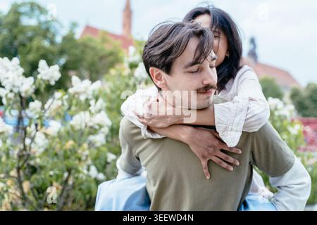 Playful interracial couple having fun in blooming spring park in European city Wroclaw Stock Photo