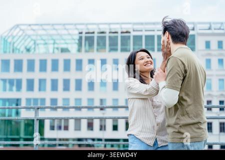 Happy diverse couple talking near modern glass architecture in European city center Stock Photo