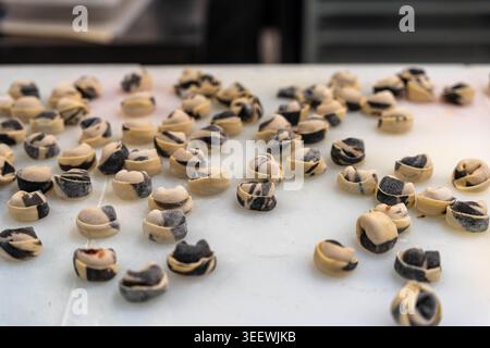 Scattered Rows Of Finished Dumplings On Countertop, Wide Top View Of Numerous Unbaked Dough Parcels Filled With Dark Sesame Paste Arranged On Floured Stock Photo