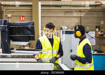Factory workers operating cnc machine in lumberyard Stock Photo