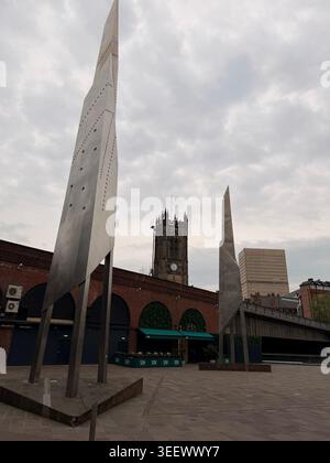 Brushed metal sculptures contrast clock tower and modern highrise buildings in Manchester. Stock Photo