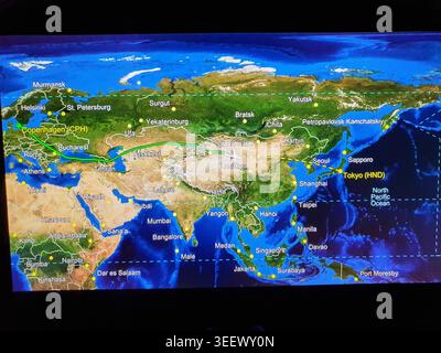 An in-flight entertainment screen displaying a flight tracking map showing the route from Copenhagen, Denmark (CPH) to Tokyo, Japan (HND). A thick Stock Photo