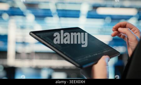 Using coding application, tablet and programmer in data center optimizing equipment rigs. Adjusting system parameters, programming script close up and IT professional in server hub camera B Stock Photo