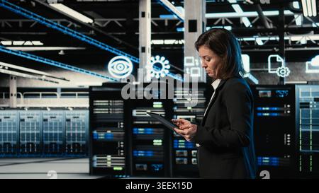 Data center engineer configuring rigs using augmented reality control panel. Woman walking in server farm, interacting with virtual holographic visualization to adjust hardware settings Stock Photo