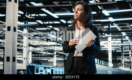Automation, tablet and engineer walking in data center, monitoring industrial systems. IT expert Server room IT professional using device to oversee network equipment performance Stock Photo